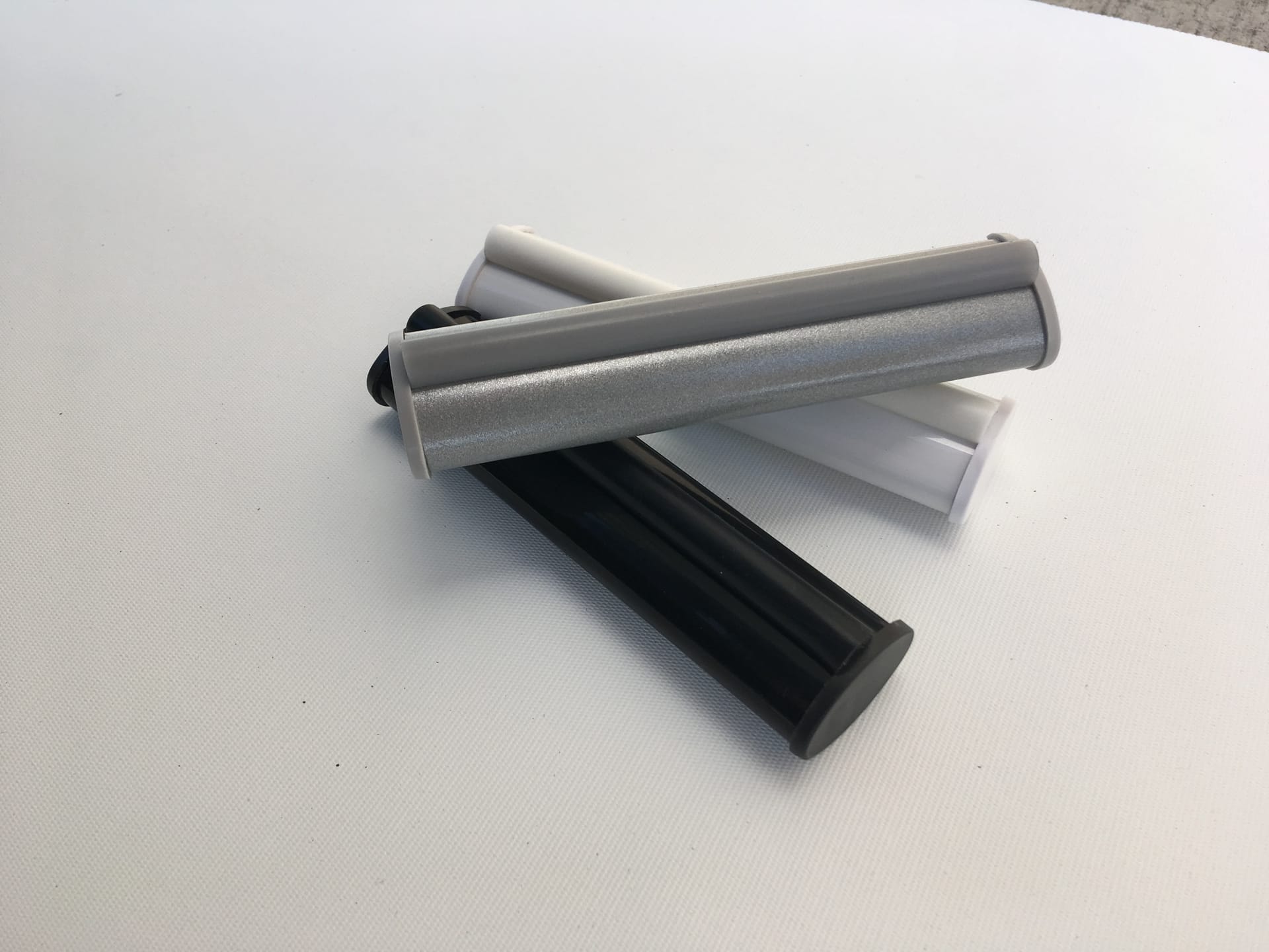 EziLux NoiseFree roller blind base rails in silver, white, and black with cushioned bumper strips