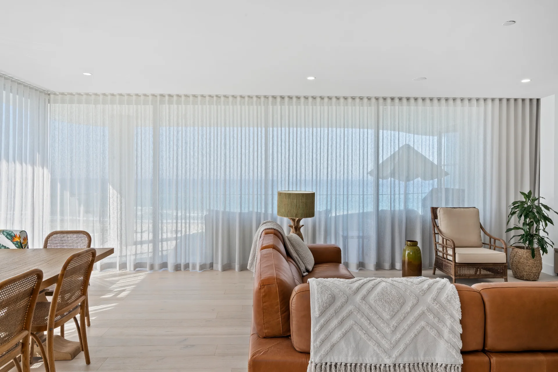 Floor-to-ceiling white sheer S-fold curtains in a bright coastal living space - soft daylight and elegant wave folds